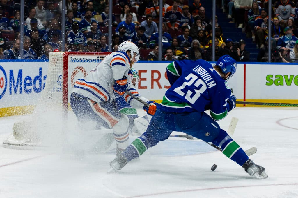 VANCOUVER, BC - MAY 20: Edmonton Oilers center Connor McDavid (97) attempting to make a shot on goal while being challenged by. Vancouver Canucks center Elias Lindholm (23) during Game Seven of the Second Round of the 2024 Stanley Cup playoffs between the Edmonton Oilers and the Vancouver Canucks on May 20, 2024, at Rogers Arena in Vancouver, B.C. (Photo by Jamie Douglas/Icon Sportswire via Getty Images)