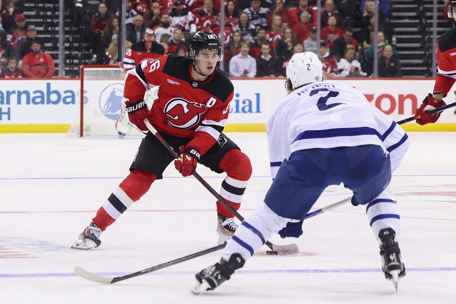 New Jersey Devils center Jack Hughes (86) skates with the puck while being defended by Toronto Maple Leafs defenseman Simon Benoit (2) during the second period at Prudential Center. Mandatory Credit: Ed Mulholland